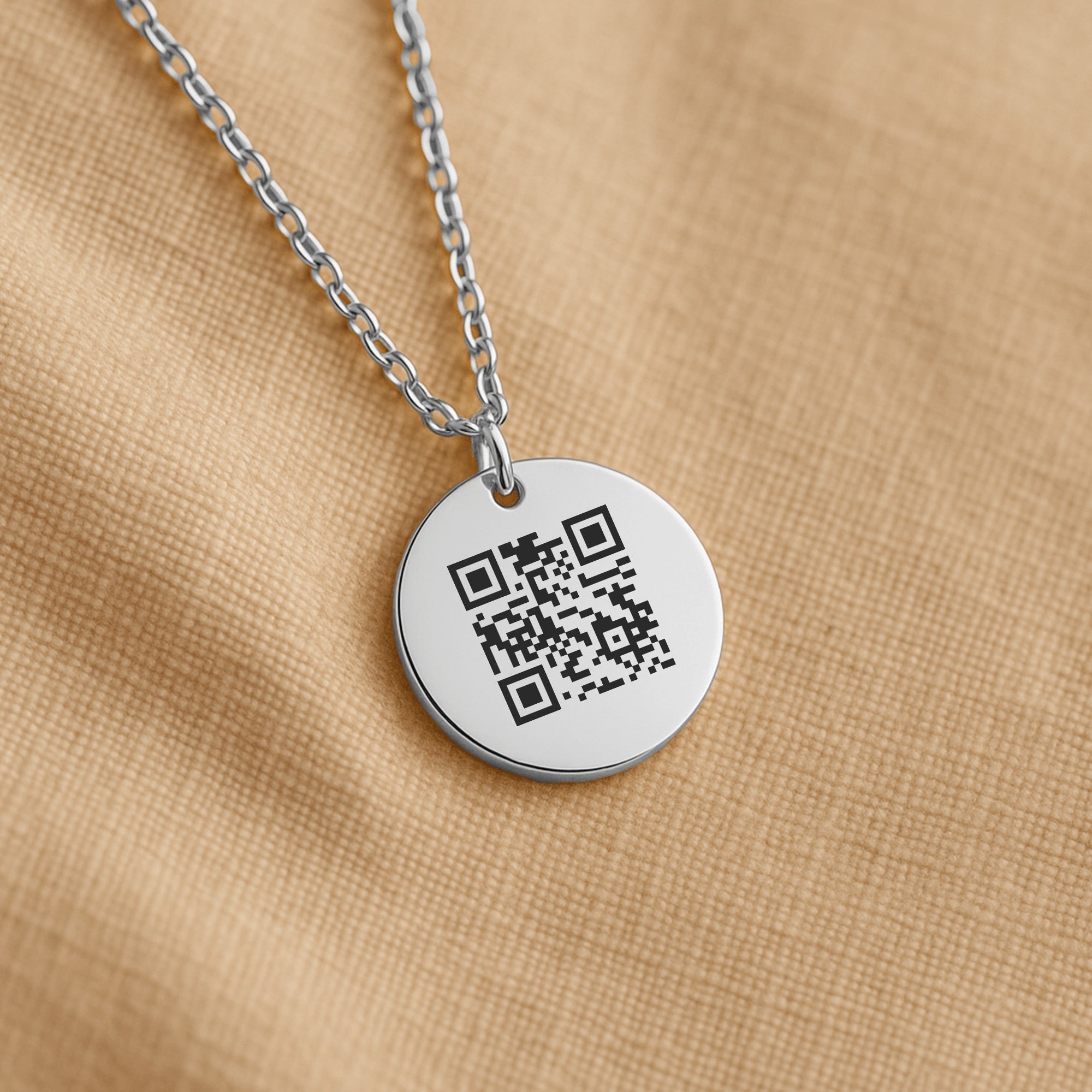 The coin pendant hanging on its chain against woven cloth.