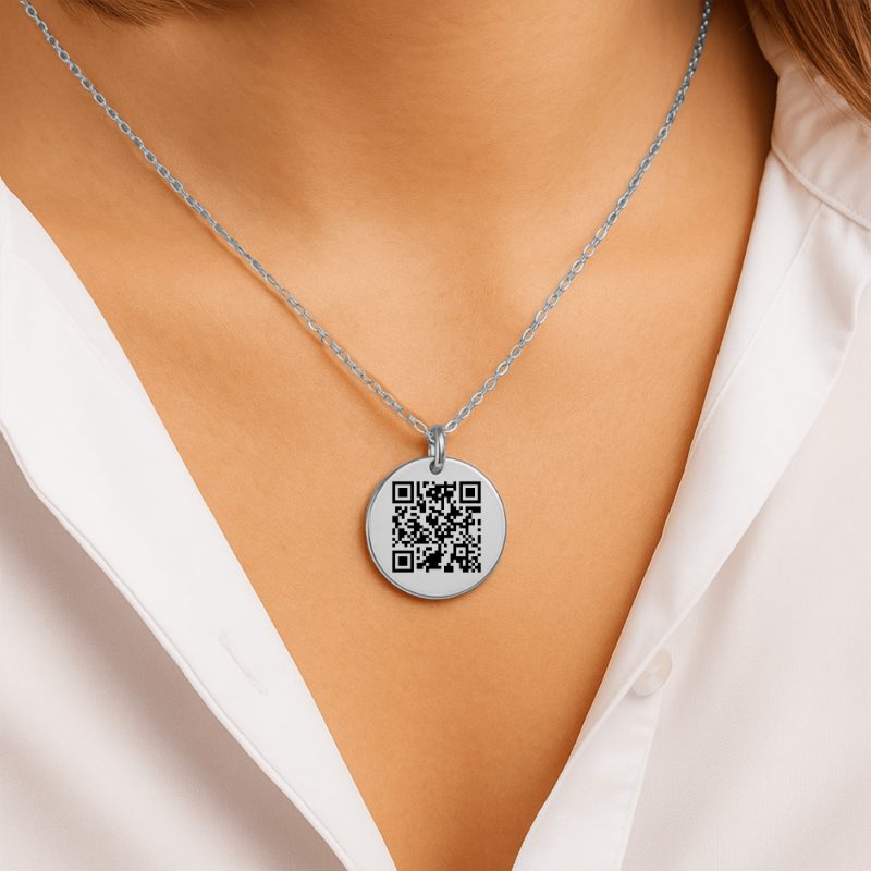 A round stainless steel coin pendant on a chain, engraved with a QR code.