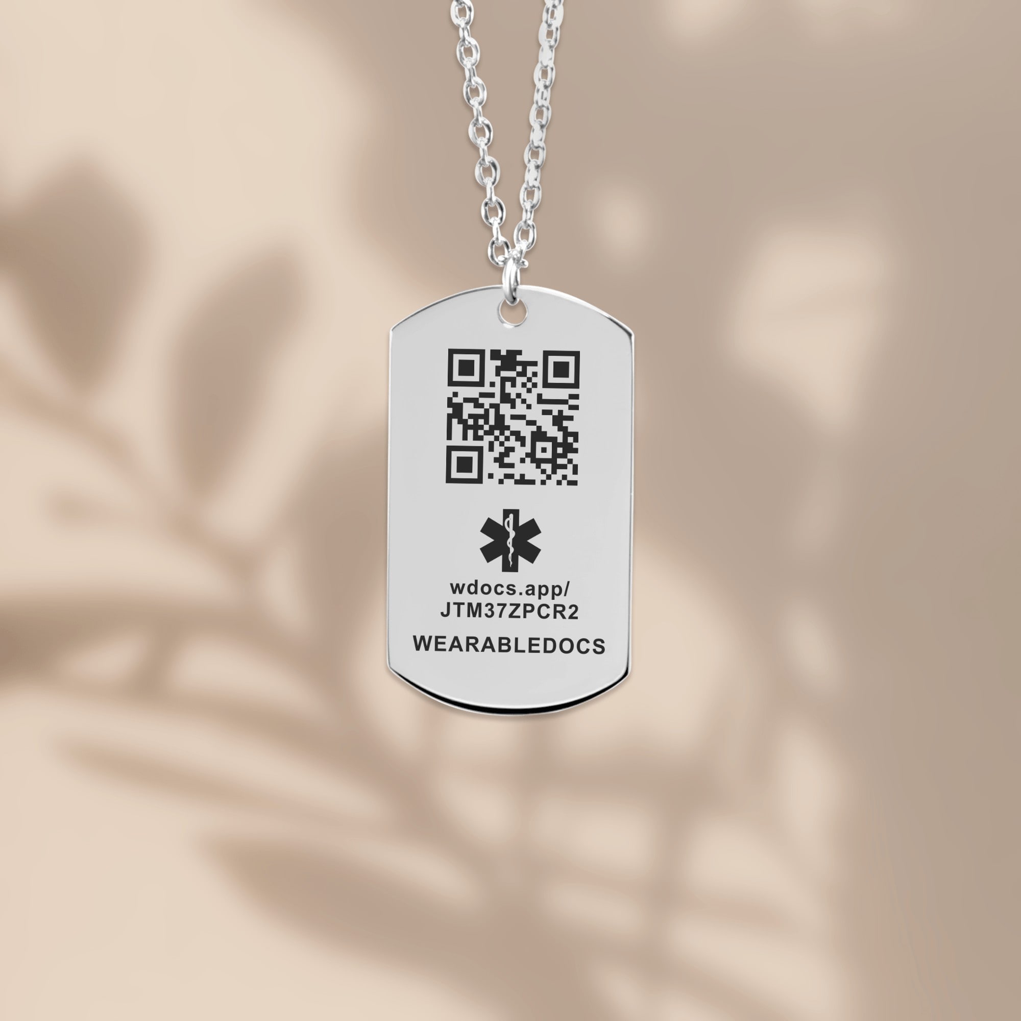 The tag pendant hanging on its chain against a plain wall.